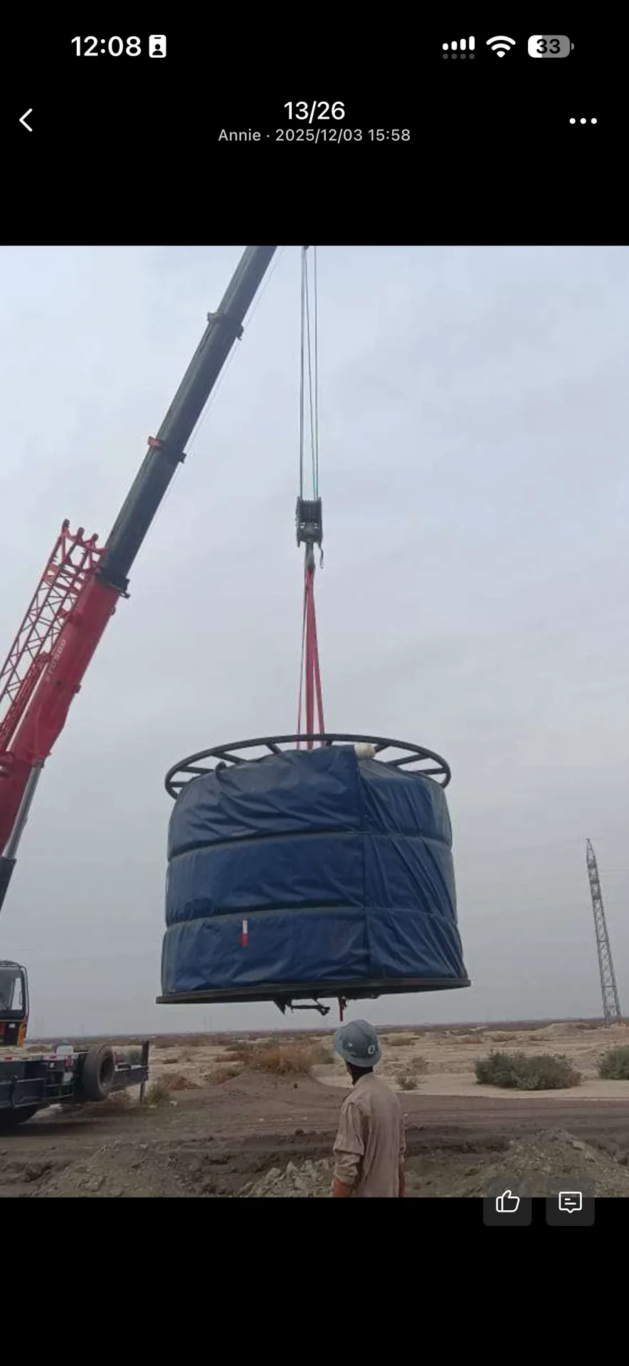 Cylindrical tank in blue quilted wrap lifted by crane at a field site